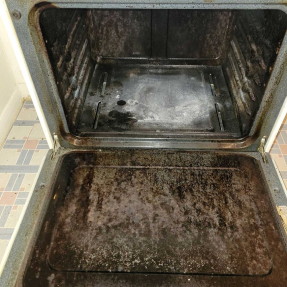 Dirty, greasy oven interior with stained enamel and bottom tray.