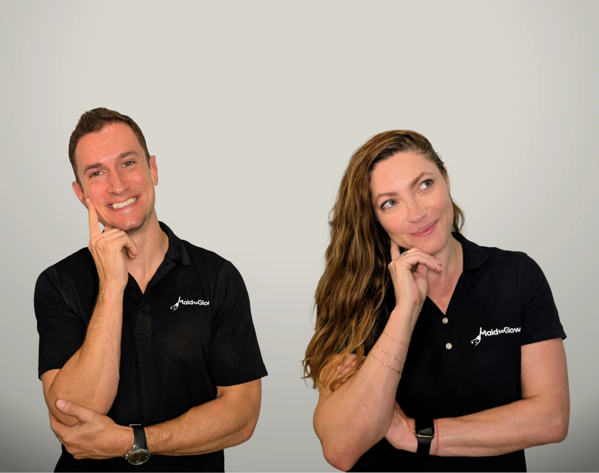 Two adults in black polo shirts posing with fingers on their chins against a neutral background.