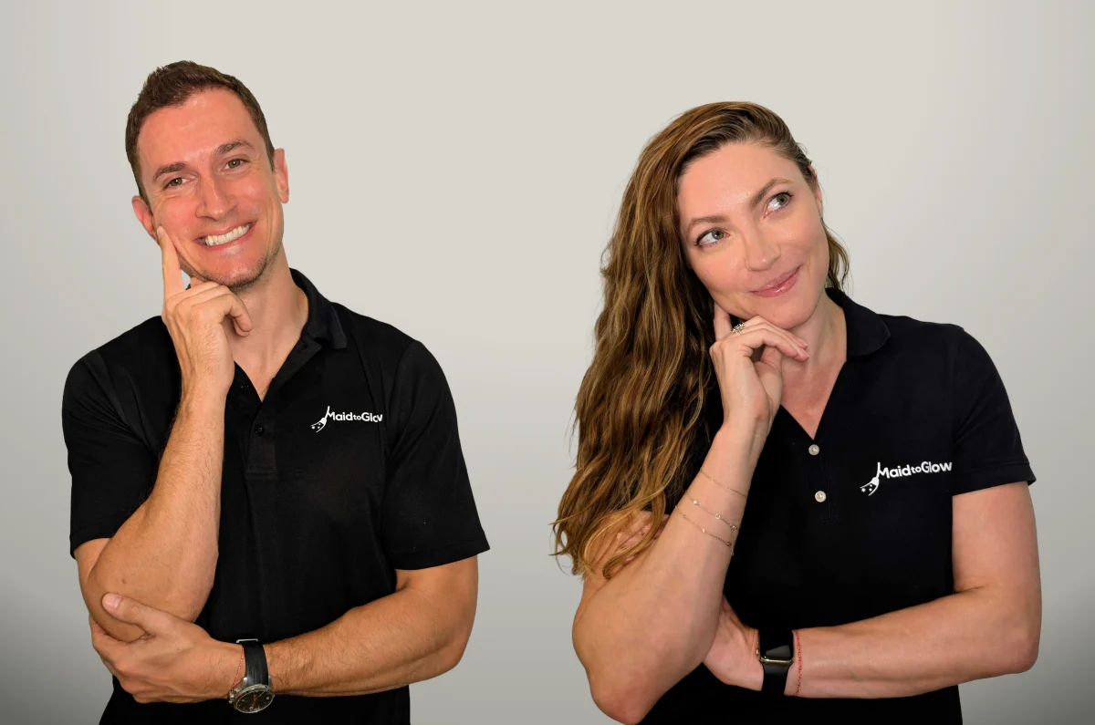 Two adults in black polo shirts with a logo, thinking pose against a light background.
